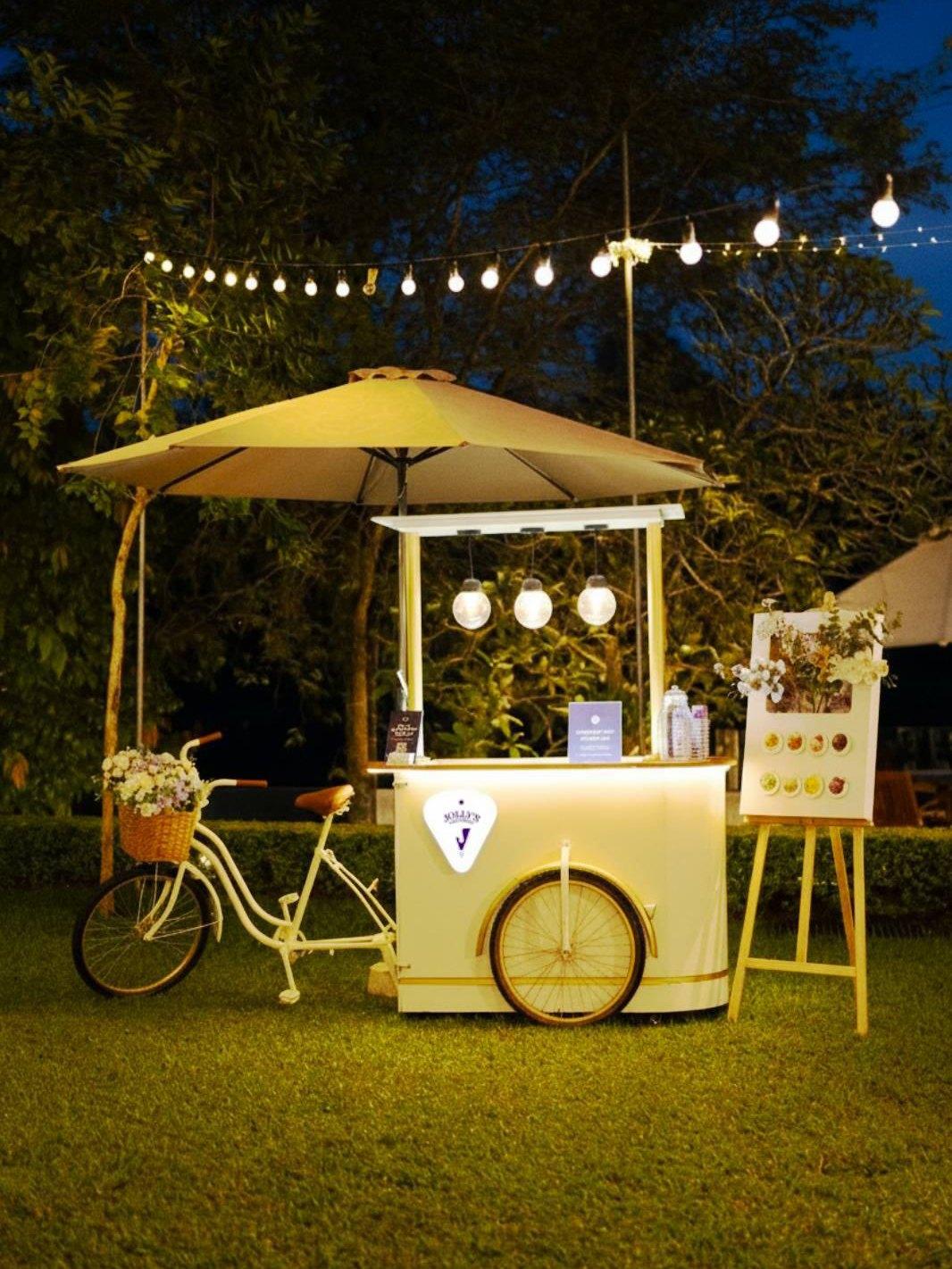 Vanilla Cream Jolly's cart with a vintage bicycle, parasol and glowing lights in an evening garden